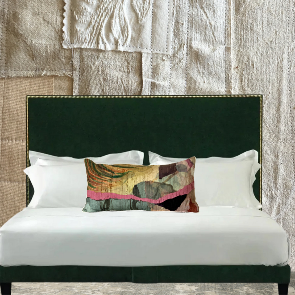 Bed with green headboard and decorative pillow against a textured wall.