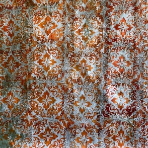 Patterned fabric with orange and white floral design on a brown background