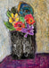 Colorful flowers in a decorative vase against a textured wall.