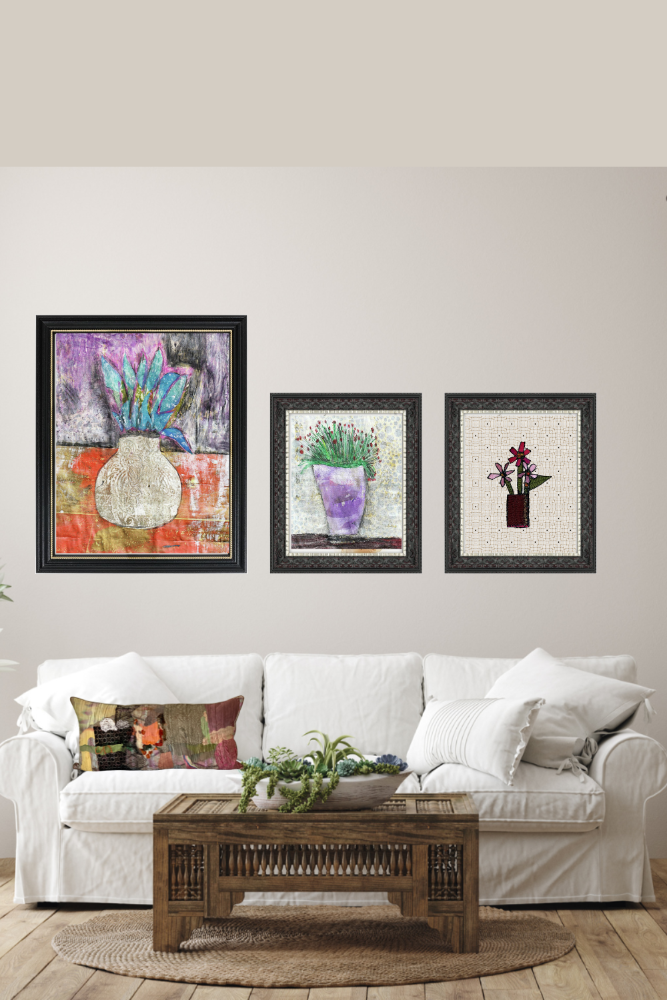 Three framed artworks on a wall above a white sofa with a wooden coffee table.