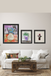 Three framed artworks on a wall above a white sofa with a wooden coffee table.