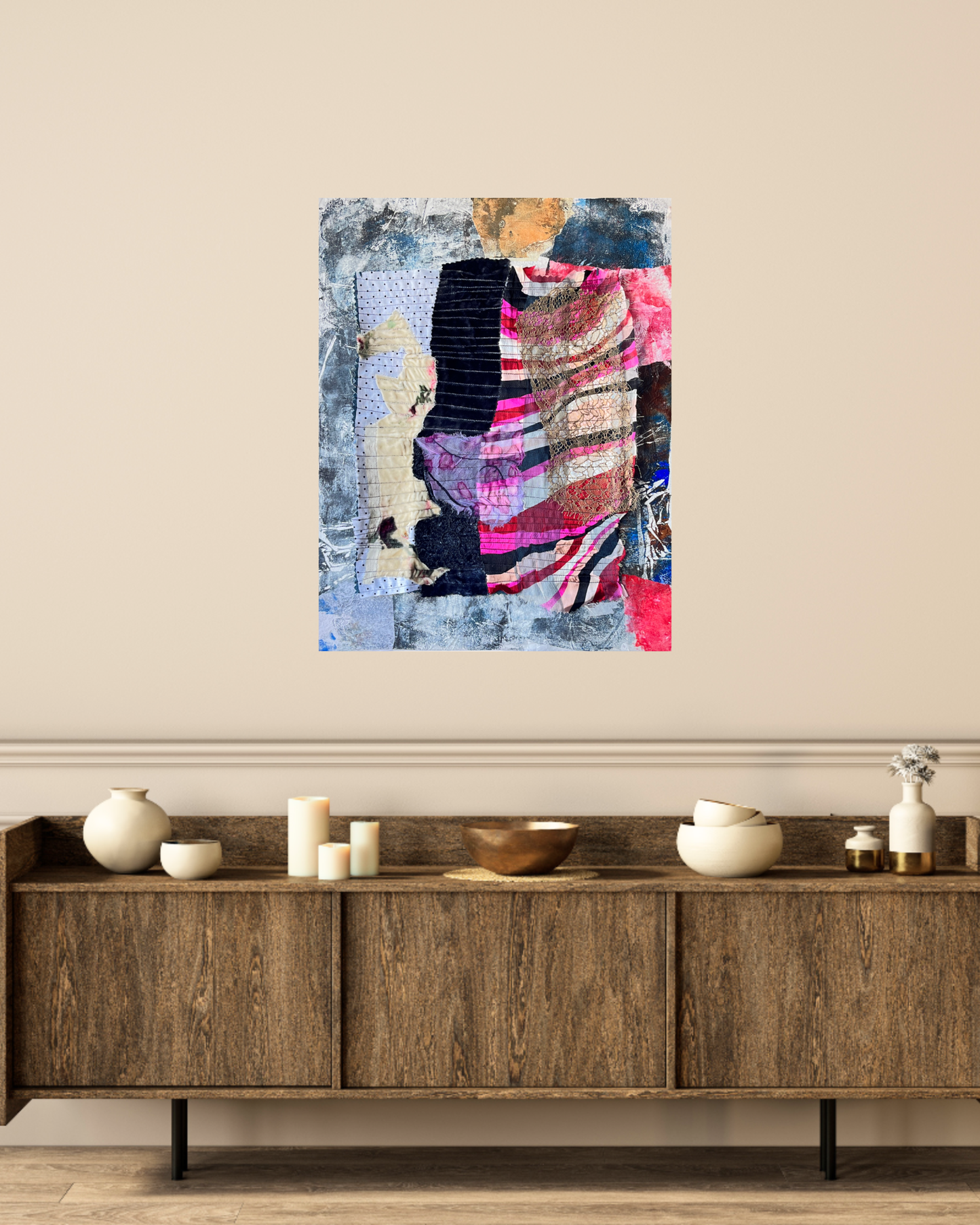 Abstract art piece on a wall above a wooden sideboard with decorative items.