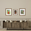 Three framed artworks above a wooden cabinet with decorative items on a beige wall.