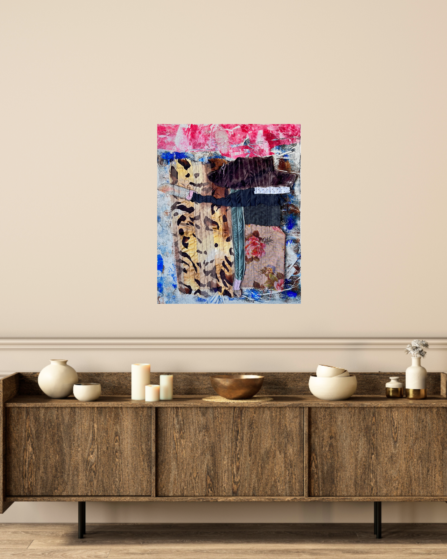 Abstract art piece on a wall above a wooden sideboard with decorative items.