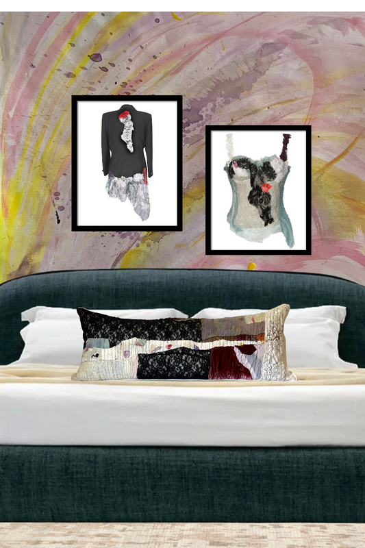 A modern upholstered bed with a long decorative pillow and framed art prints above, featuring custom wall decor with artistic fashion designs.