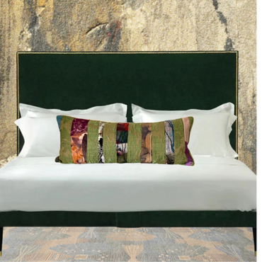 Bed with decorative pillows against a textured wall