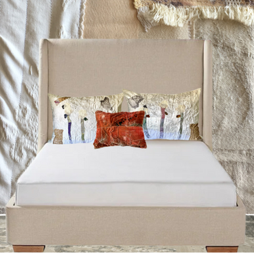 Beige upholstered bed with white mattress and decorative pillows against a textured wall.