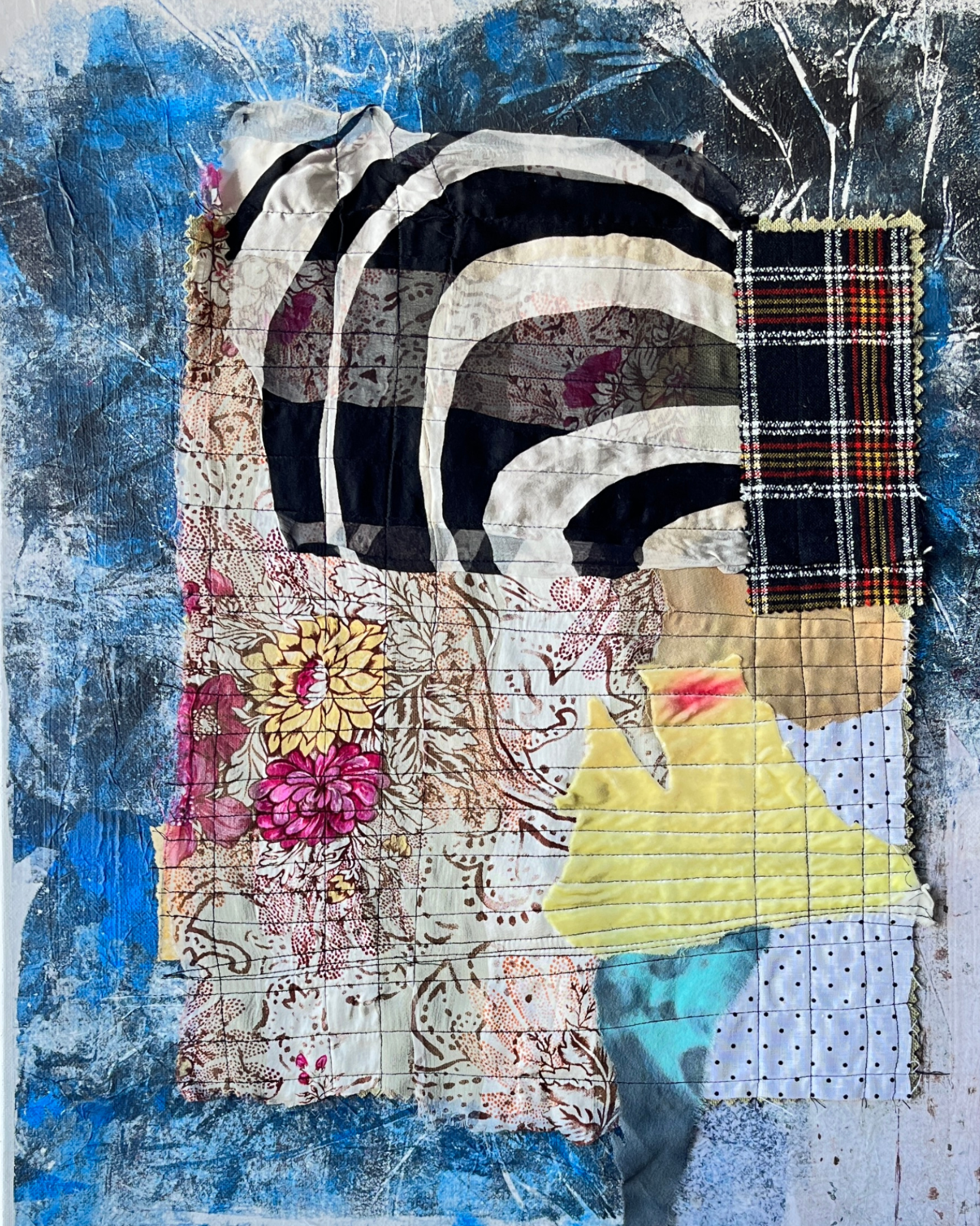 Collage art with fabric pieces featuring a face and floral elements on a textured blue background.