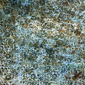 A close-up of a batik fabric with a dense, organic leaf pattern in earthy brown, olive green, and light blue-gray tones.