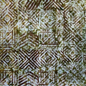 A close-up of batik fabric with a geometric and floral pattern in earthy brown, olive green, and off-white.