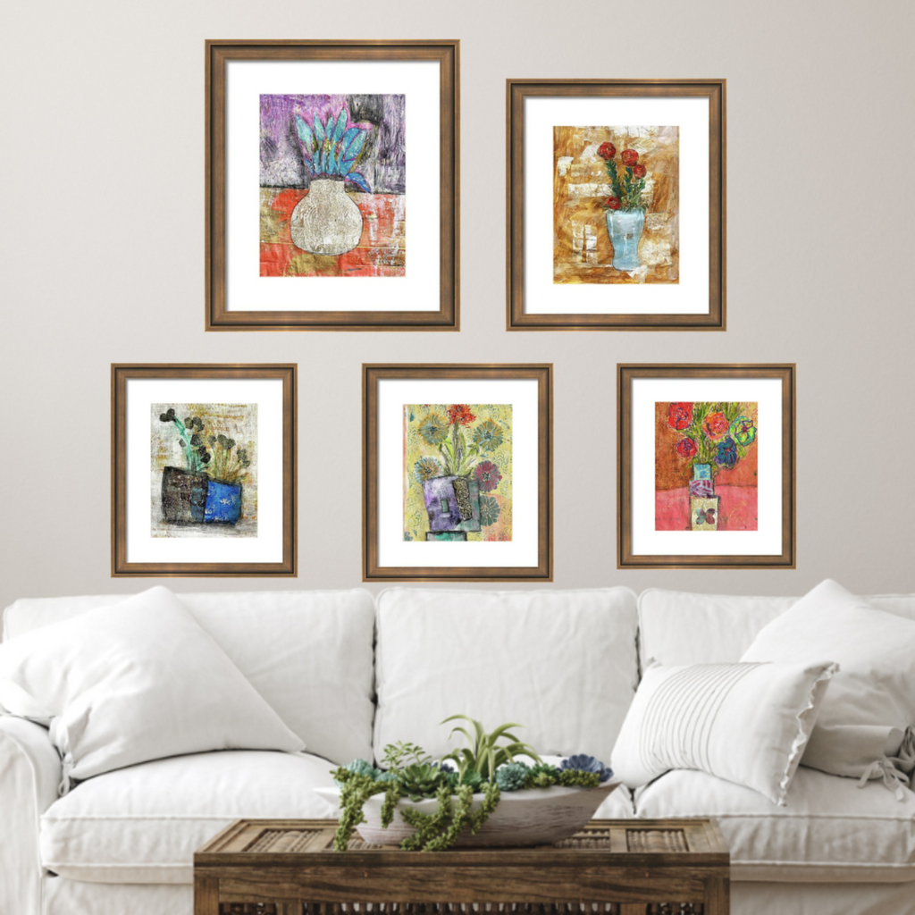 Five framed artworks above a white sofa in a living room setting.