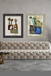 Two framed artworks on a gray wall above a beige sofa.