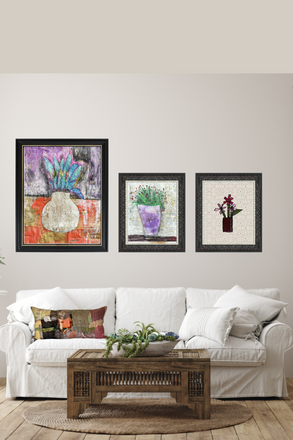 Three framed artworks on a wall above a white sofa with a wooden coffee table.