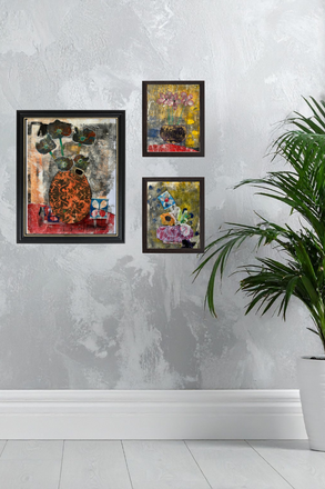 Three framed artworks on a textured wall with a plant in the foreground.