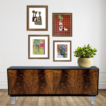 Wooden sideboard with framed artwork and a plant on a white wall.