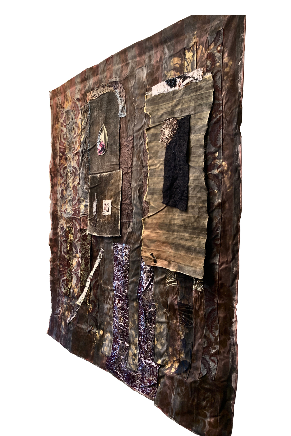 A square mixed-media textile artwork featuring layered fabrics, patches, and printed elements in earthy brown, black, beige, and purple tones, shown against a plain white background.