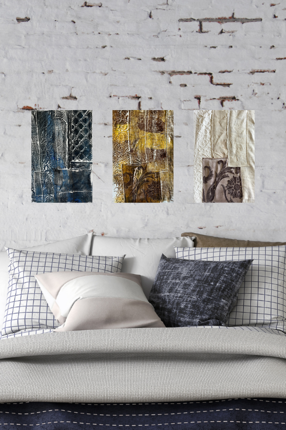 Three abstract paintings on a wall above a bed with pillows.