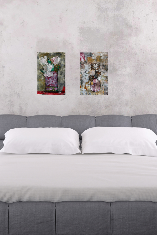 Two floral paintings above a bed with gray headboard and white bedding.