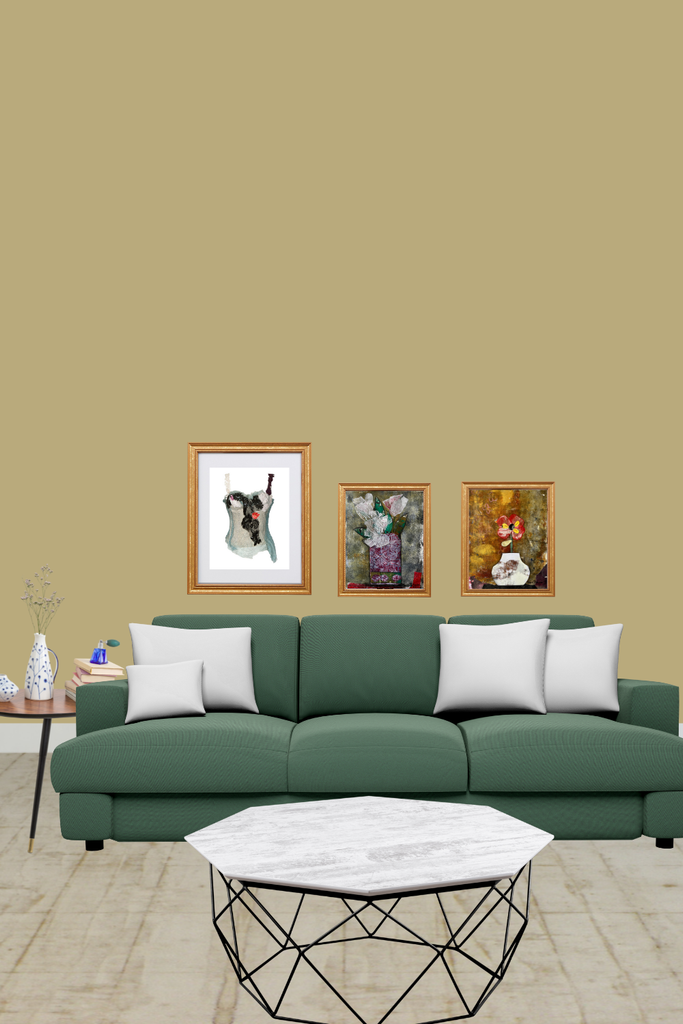 Green sofa with white cushions in a living room setting with framed pictures on the wall.