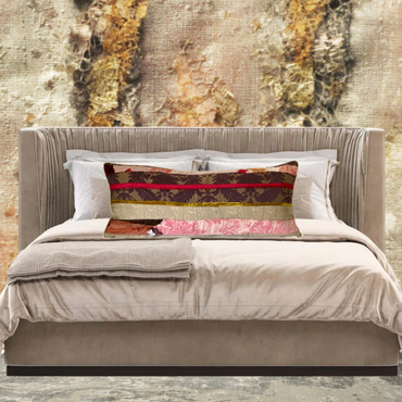 Neatly made bed with decorative pillows against a textured wall.