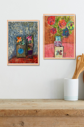 Two colorful abstract paintings on a white wall above a wooden shelf.