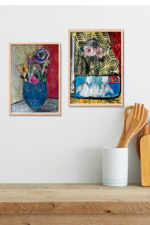 Two framed artworks on a wall above a wooden shelf with kitchen utensils.