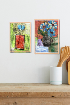 Two framed abstract artworks on a wall above a wooden shelf with kitchen utensils.