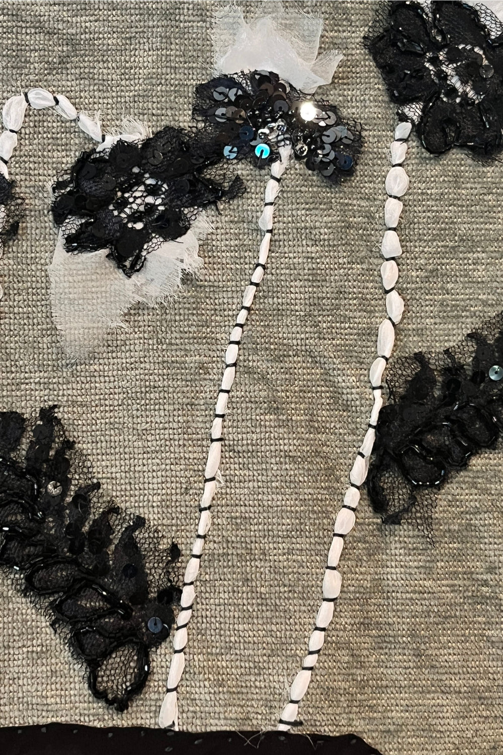 Decorative headband with black floral embellishments and white beads on a textured background