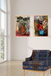 Two abstract paintings on a wall above a patterned armchair in a room with large windows.