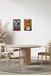 Dining area with a round wooden table and chairs, featuring two wall-mounted artworks.