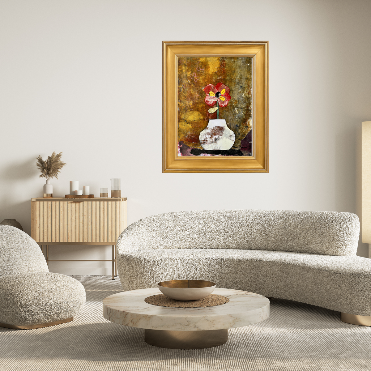 Framed still life artwork featuring a red and yellow flower in a white vase against a textured gold and brown background, set in a gold frame on top a white modern sofa.