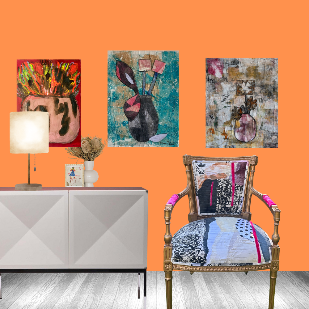 Decorative chair with colorful cushions in front of an orange wall with three abstract paintings.