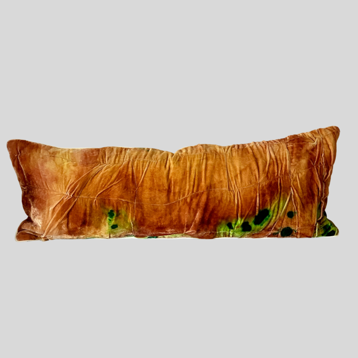 Brown pillow with green and black abstract pattern on a light gray background