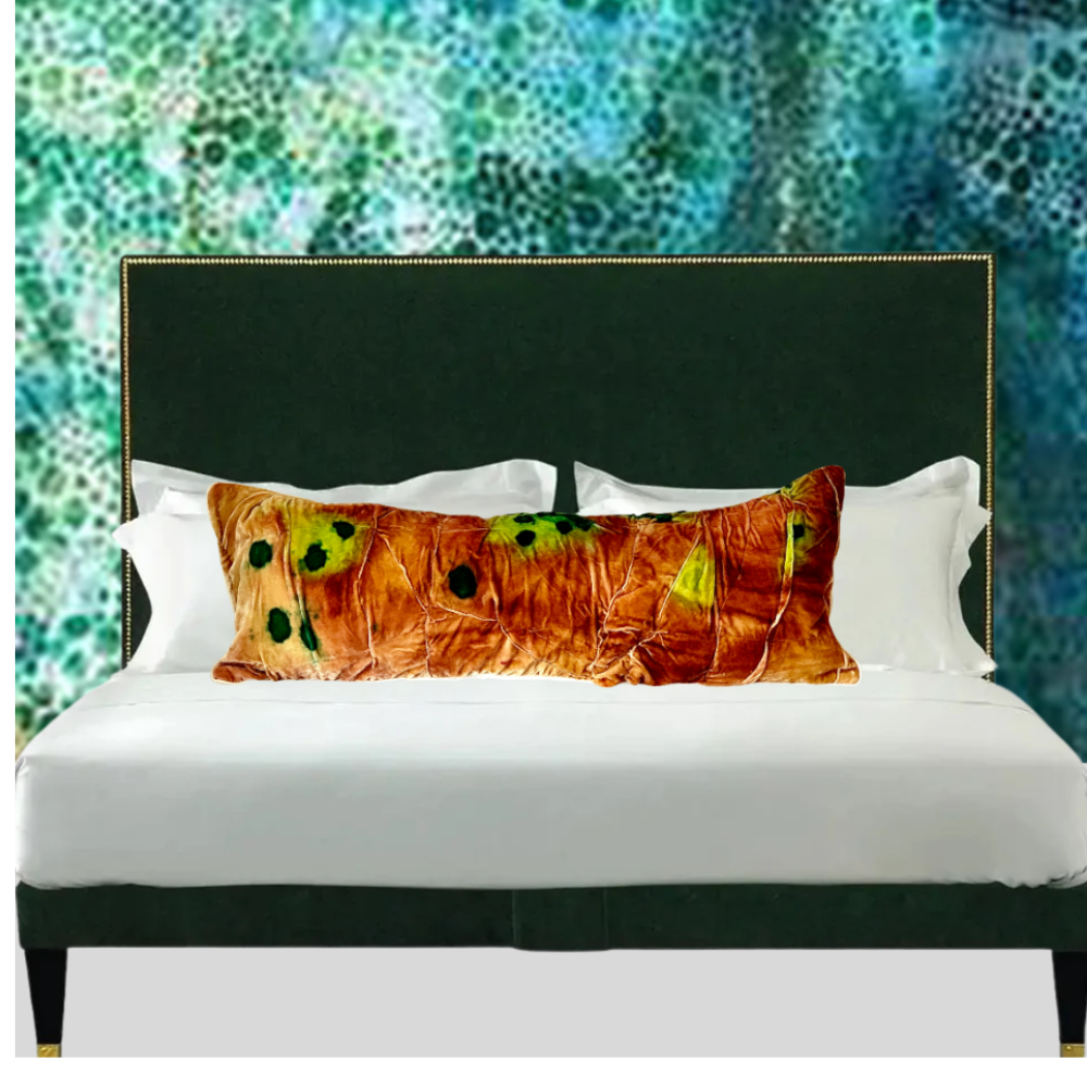 Bed with decorative pillows against a textured green and blue wall