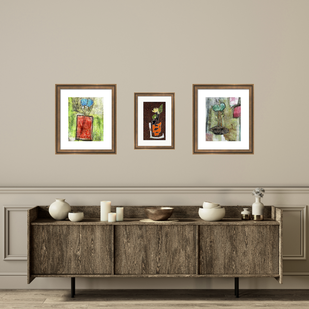 Three framed artworks above a wooden cabinet with decorative items on a beige wall.
