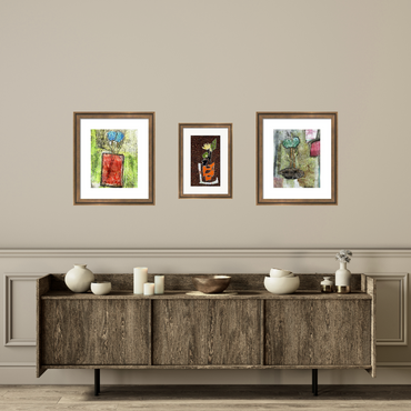 Three framed artworks above a wooden cabinet with decorative items on a beige wall.