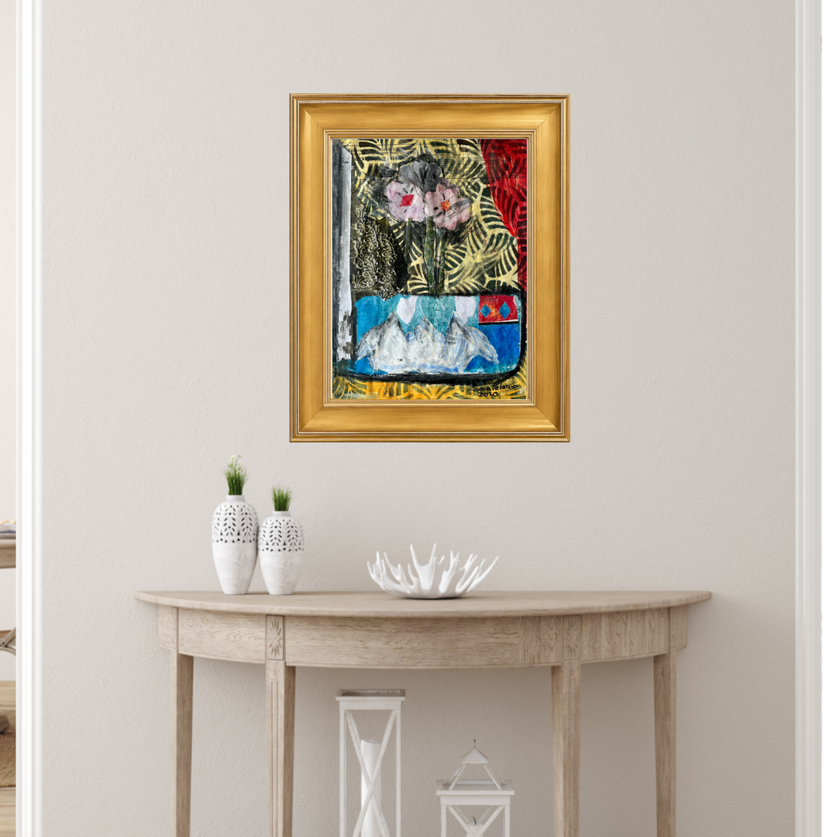 A framed abstract painting with a gold frame hangs on a light beige wall above a wooden console table with decorative vases and a white bowl.