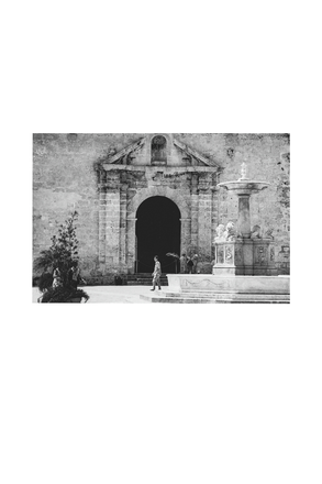 Vintage black and white photo of a classical building in Cuba with a fountain and people around.