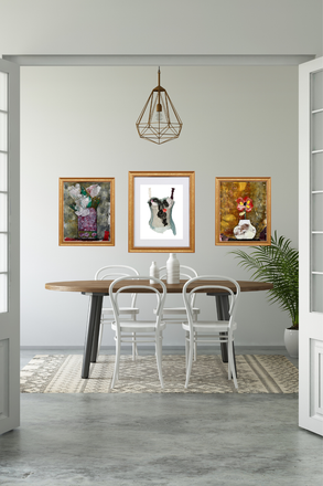 Dining room with a table and chairs, framed artwork on the wall, and a plant.