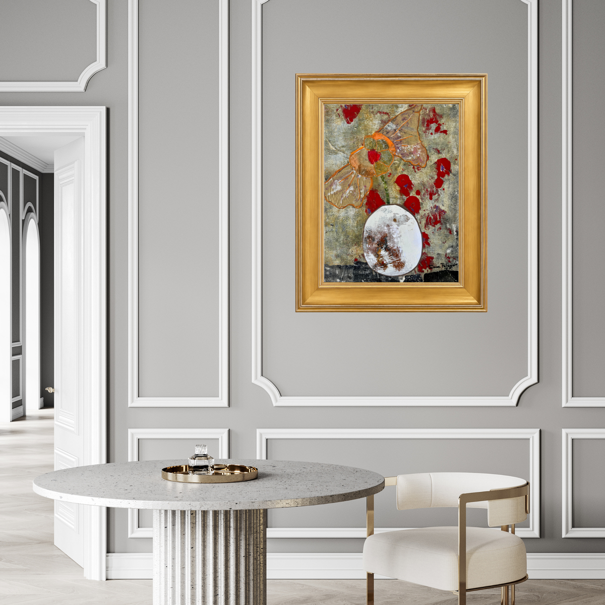 Framed abstract art print featuring a textured background with red splatters, a butterfly motif, and a white oval shape, presented in a gold frame in a modern dining room