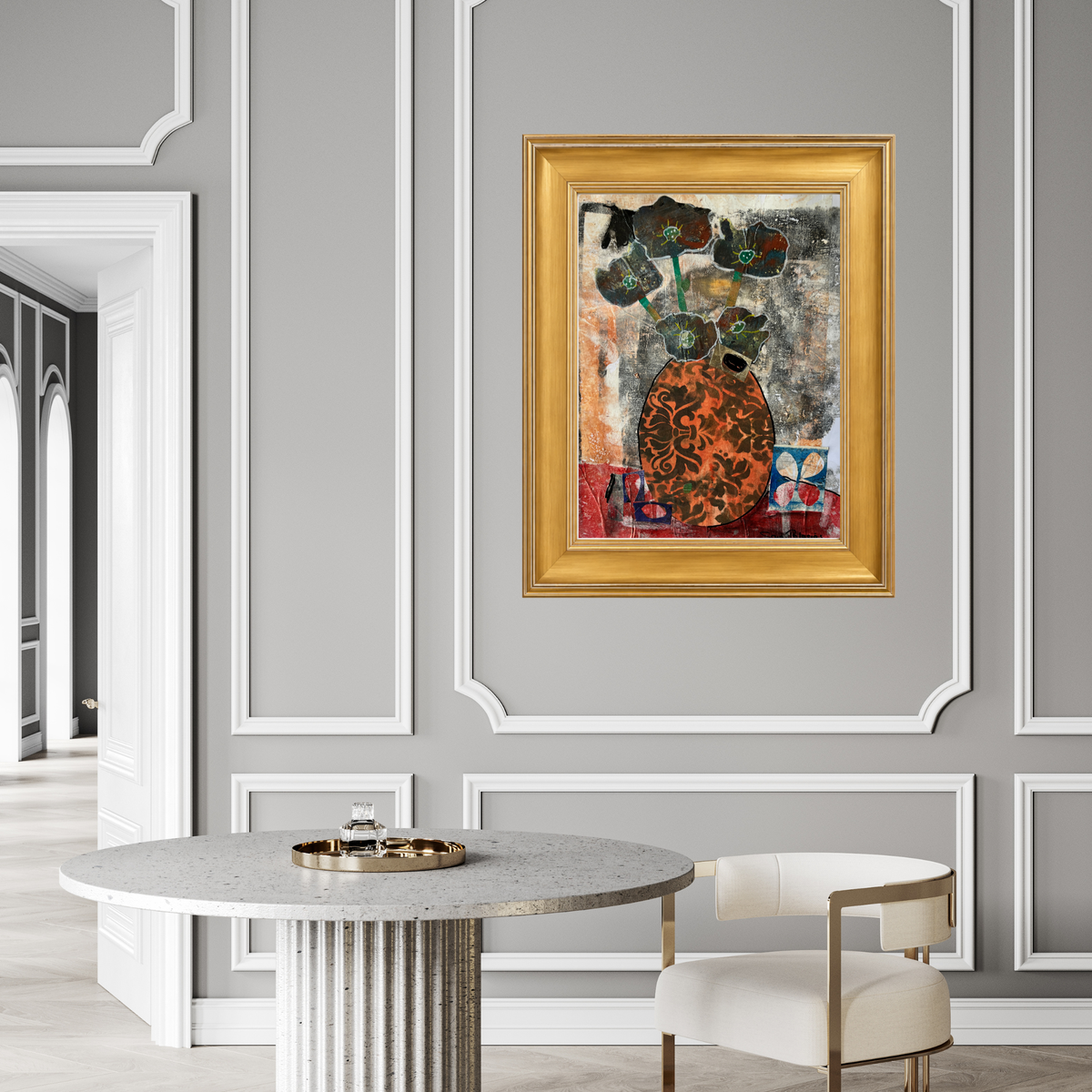 Framed abstract art print featuring a stylized orange and black patterned vase with dark flowers on a textured multicolor background, enclosed in a white mat and a gold frame in a grey and white dining room