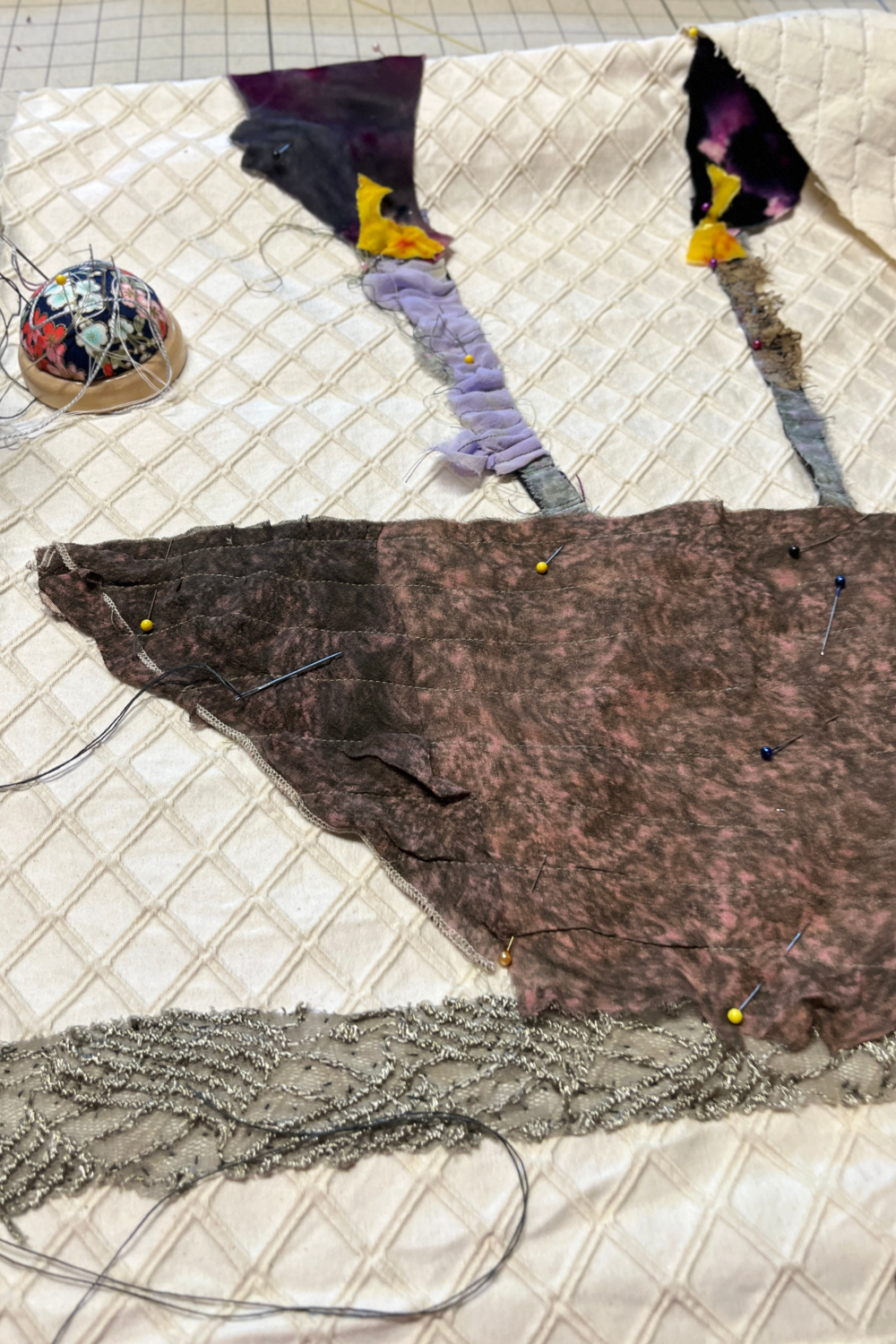 Textile art piece with fabric swatches and a bear-shaped fabric on a tiled floor.