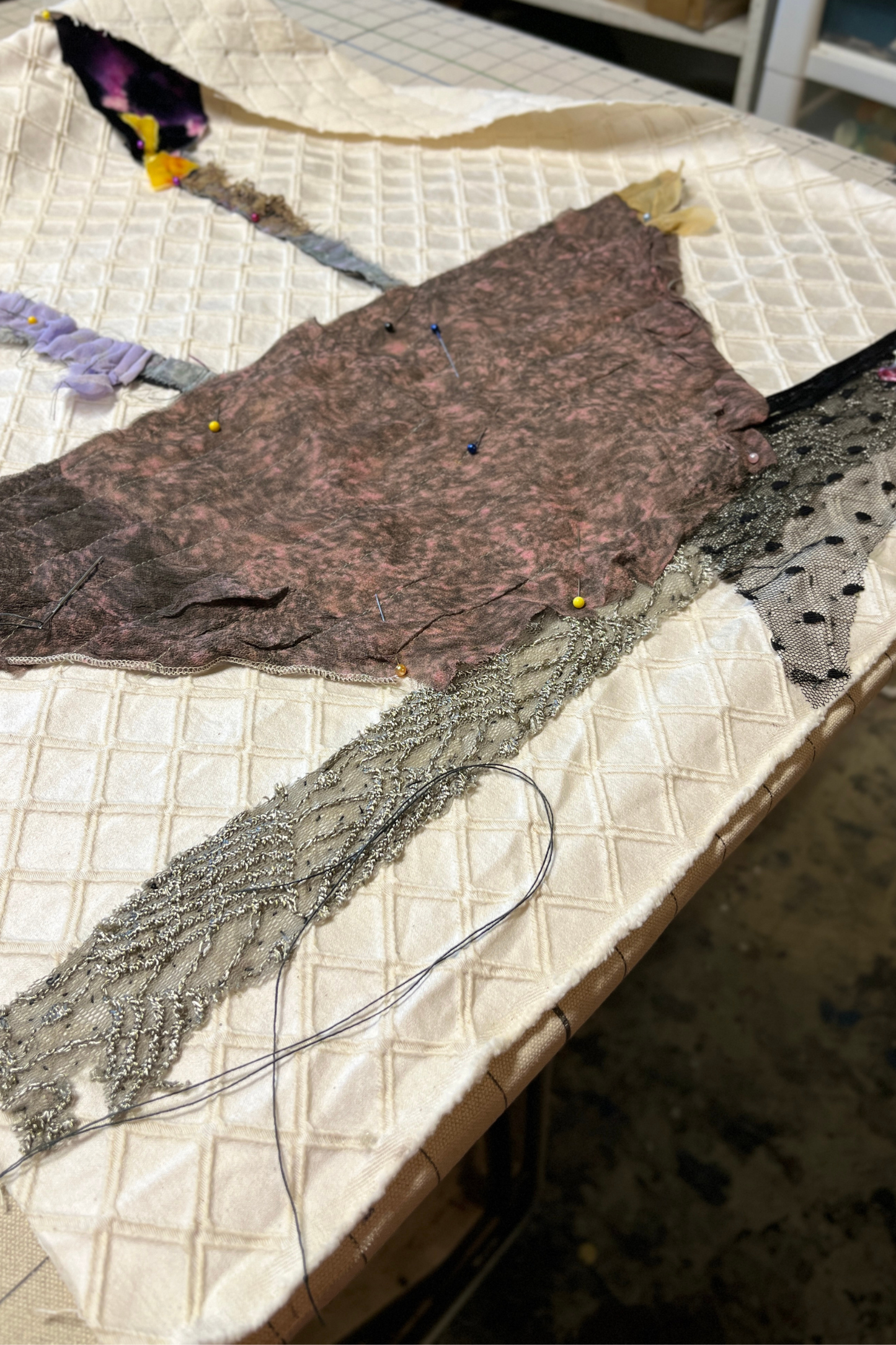 Textile materials on a quilted surface with visible threads and fabric pieces.