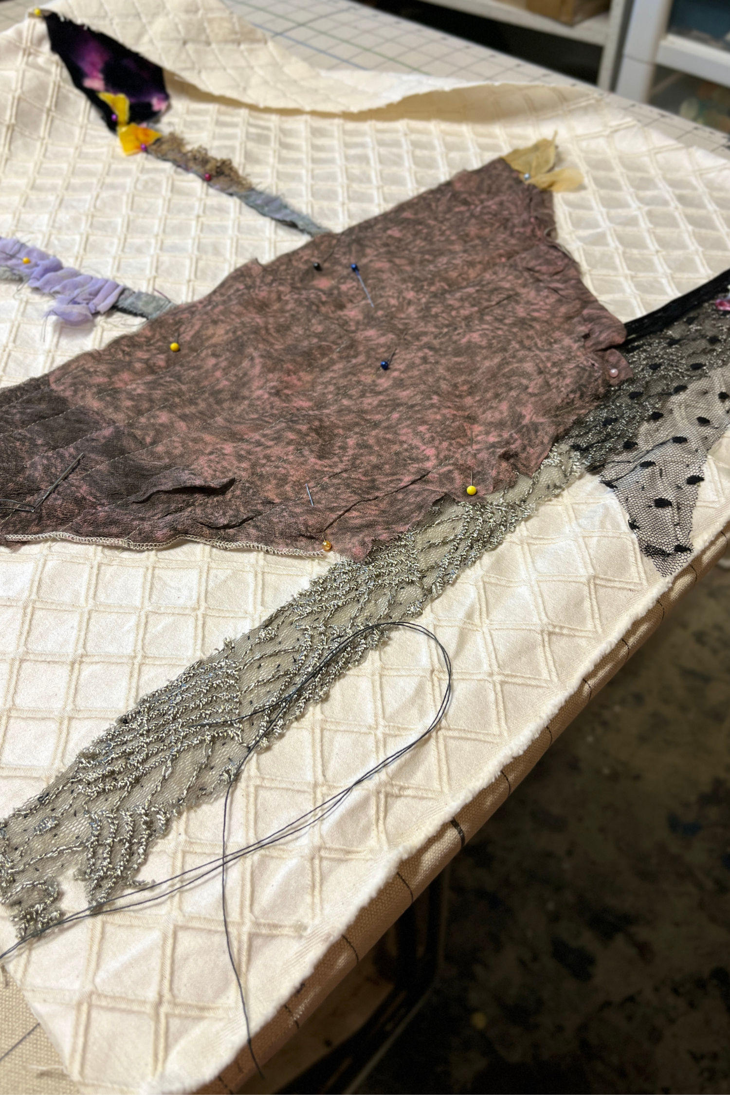Textile materials on a quilted surface with visible threads and fabric pieces.