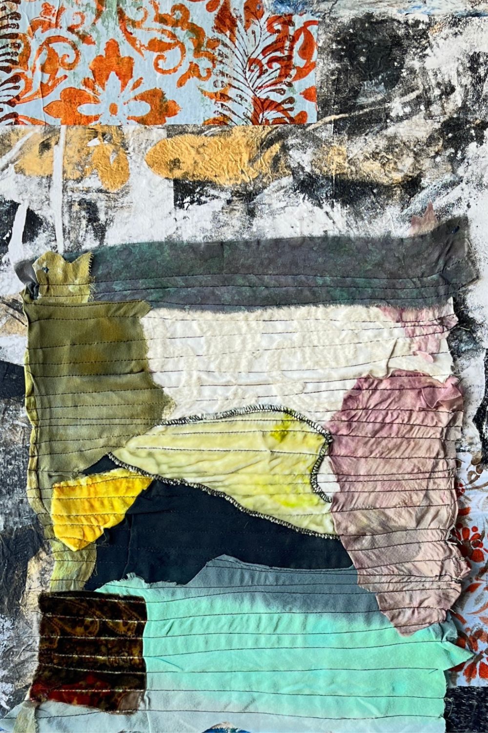 Abstract mixed-media textile artwork with layered fabric panels, distressed paper, and printed patterns in black, white, gray, orange, yellow, pink, teal, and brown.
