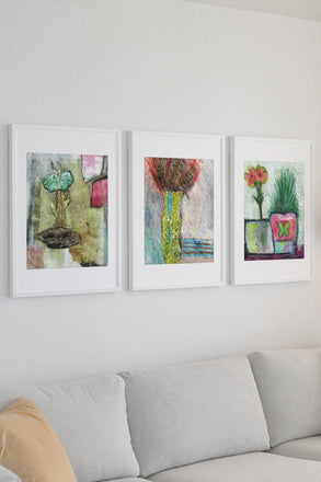 Mixed media collage titled Ice Moon by Sara Palacios. The piece showcases a tall green vase with blue accents holding dark, richly patterned blooms, surrounded by textured strokes in cool blues and soft pinks. The layered background and dramatic color contrast evoke a wintery, elegant mood.